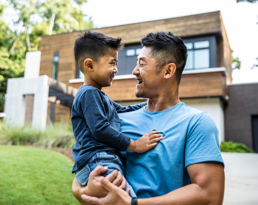 Father holding son in front of modern home