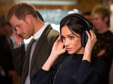 Britain's Prince Harry and his fiancée US actress Meghan Markle listen to a broadcast through headph...