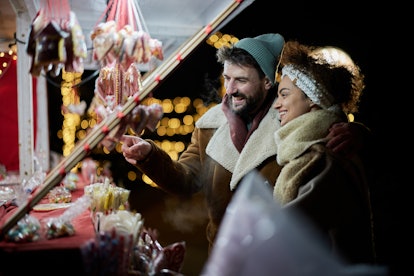 Happy couple choosing the right sweets for them during the night on Christmas market.