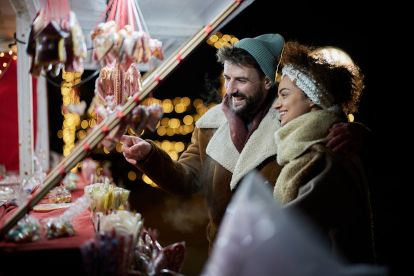 Happy couple choosing the right sweets for them during the night on Christmas market.