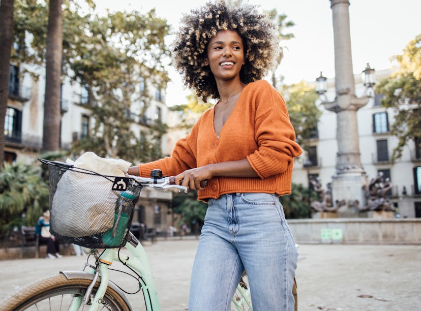 Young African American woman exploring Barcelona by a bike and enjoying her journey.