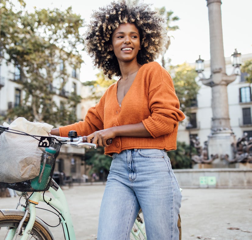 Young African American woman exploring Barcelona by a bike and enjoying her journey.