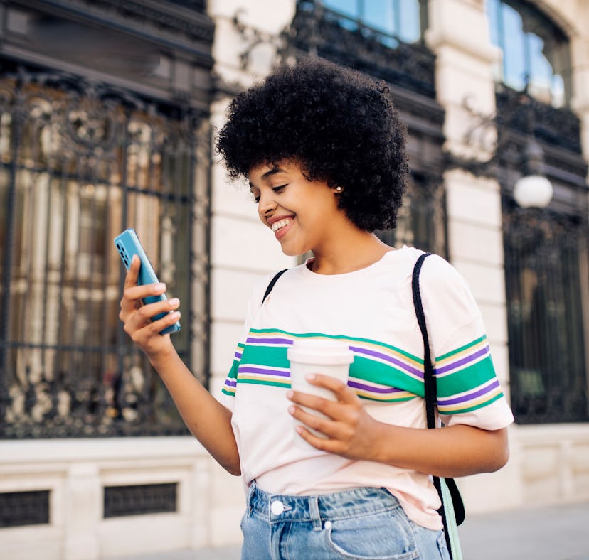 A woman swipes through different swipe photo trends on TikTok, while holding a coffee.