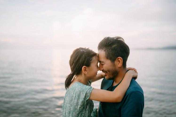 Happy father and young daughter embracing on beach at sunset, Japan