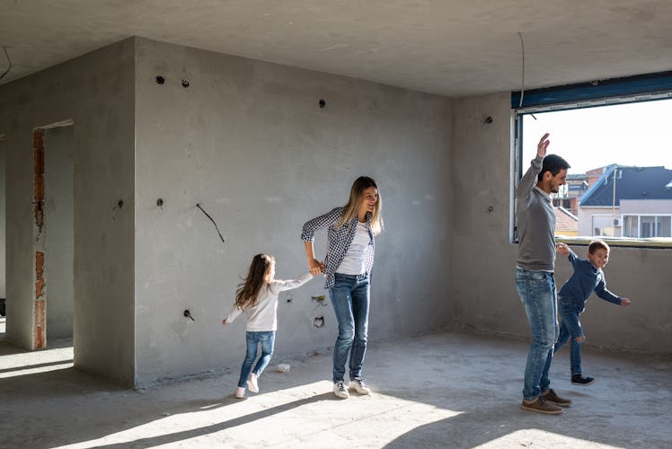 Young happy family celebrating buying their new, empty apartment. Mother, father, boy and girl are d...