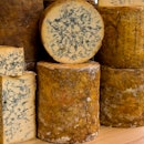 A stack of blue cheese on a market stall.