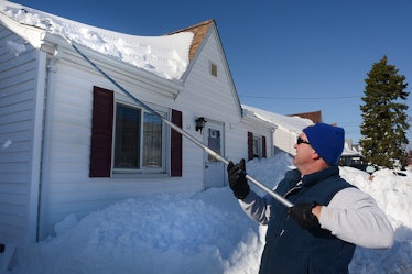 BUFFALO, NY, UNITED STATES - NOVEMBER 21: A resident works to remove snow from the roof on November ...