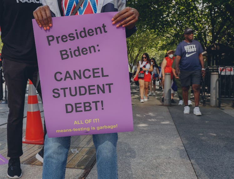 Members of the general public walk by as student loan debt holders take part in a demonstration outs...