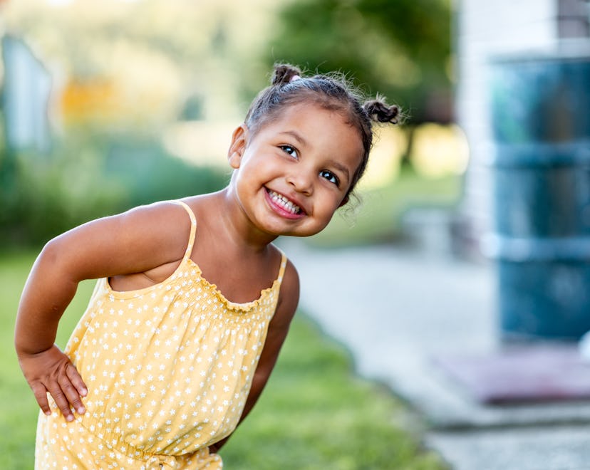 Portrait of a cute little cheerful mixed race girl in a yellow summer rummper.