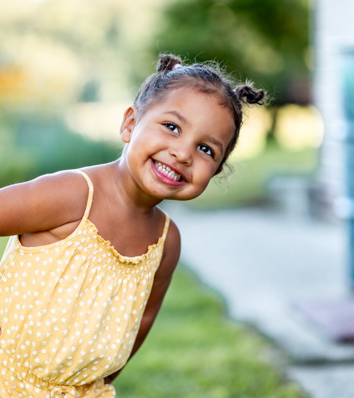 Portrait of a cute little cheerful mixed race girl in a yellow summer rummper.