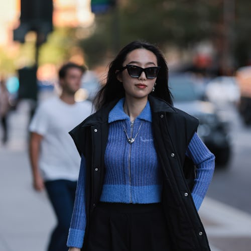 NEW YORK, NEW YORK - SEPTEMBER 10: Fashion Week Guest seen wearing a blue cardigan, black vest and b...
