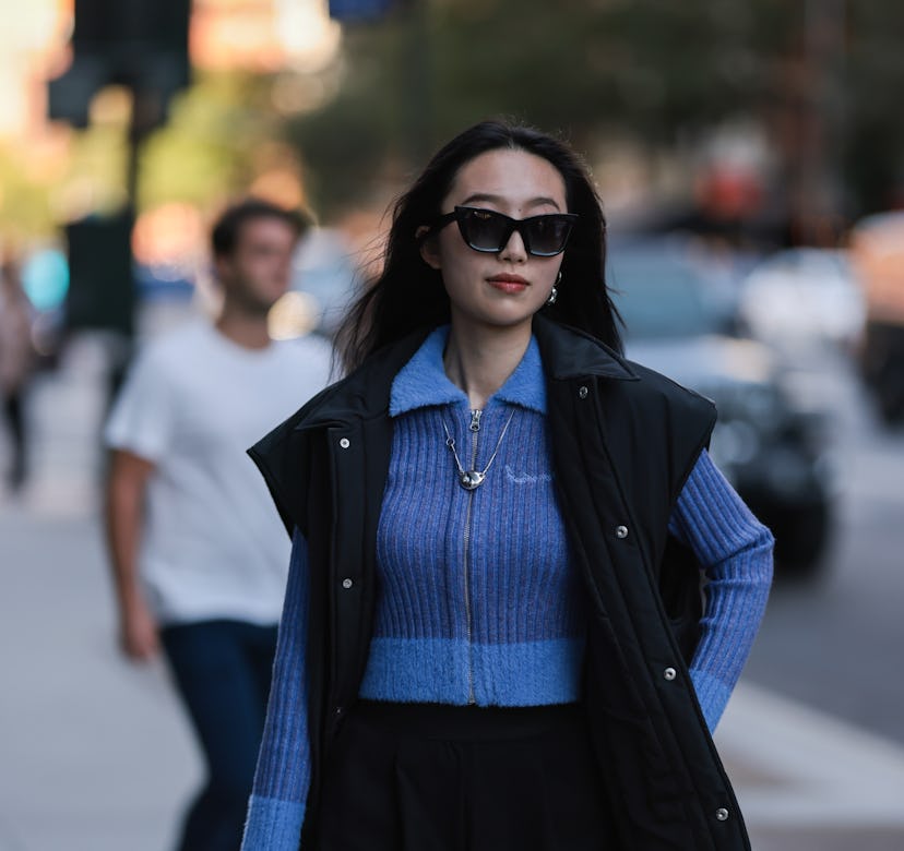 NEW YORK, NEW YORK - SEPTEMBER 10: Fashion Week Guest seen wearing a blue cardigan, black vest and b...