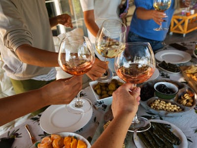 Wine glasses and appetisers on the table. Female friends celebrating birthday.