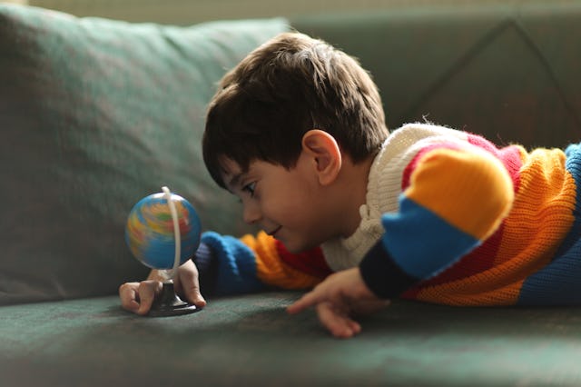 A young boy looks at globe in bedroom. A new study found that kids who dream big are more likely to ...