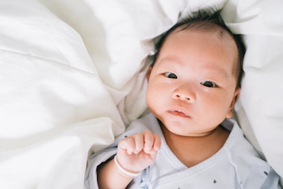 close-up of a baby lying on the bed, how to get the mucus out of the baby's nose
