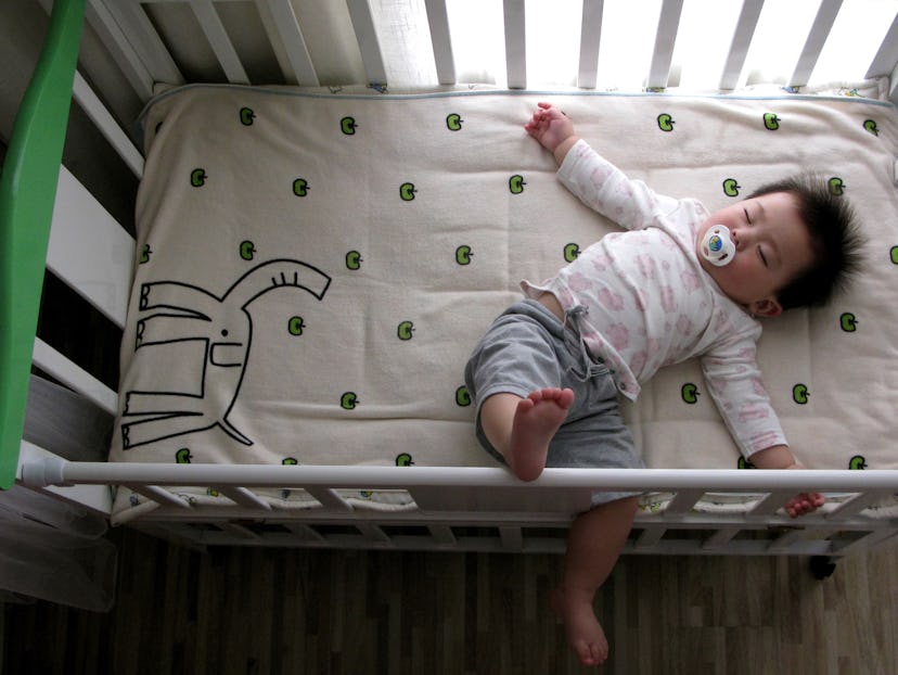 a baby in a crib sleeping in an article about when to start sleep training