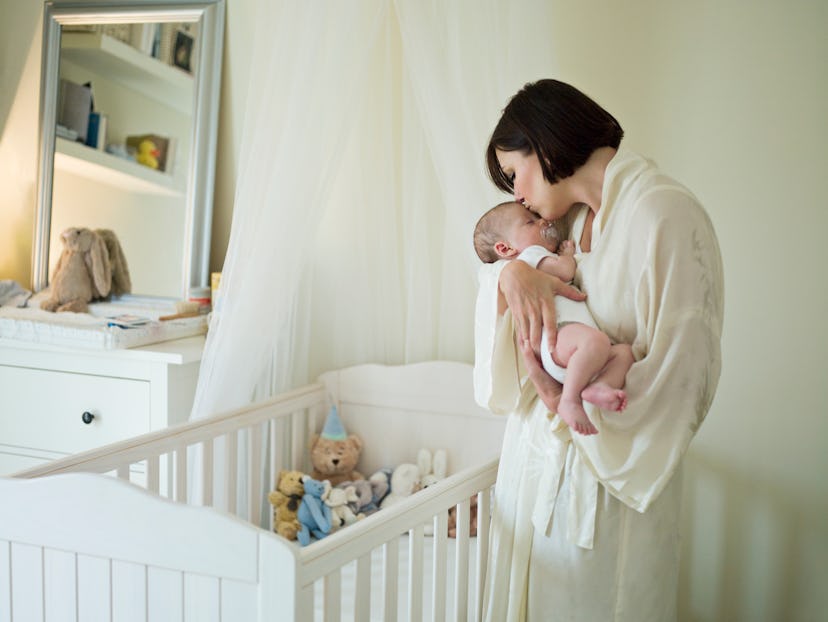 a mom and baby about to tuck the baby in an article about when to start sleep training