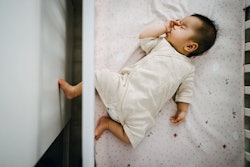 Cute Asian baby girl sucking thumb while sleeping peacefully in baby cot