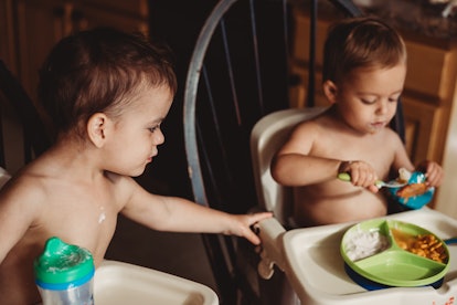 twin babies eating food together in an article about the best thanksgiving foods for babies