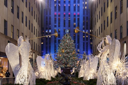 The Rockefeller Center Christmas tree lit up, surrounding by illuminated angels.