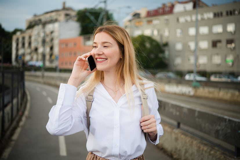 Portrait of a beautiful, young woman walking outdoors and talking on mobile phone