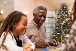 A grandfather and young granddaughter sitting next to each other at the table for a holiday meal, go...