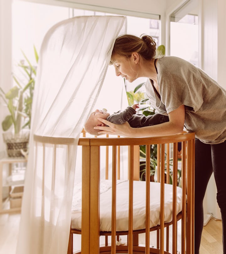 a woman puts baby to sleep in a bassinet in an article about when is baby too big for the bassinet?