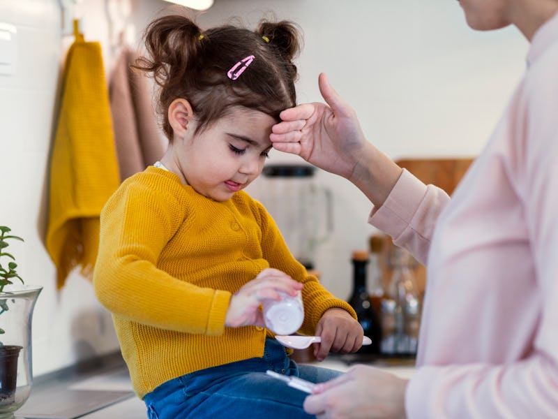 Mother is taking care of her sick little girl.She measures her temperature and wipes her nose.