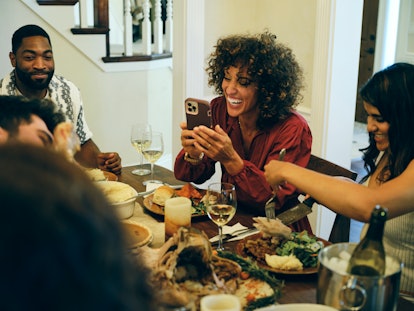A group of friends celebrating Thanksgiving dinner together in a round up of Thanksgiving text messa...