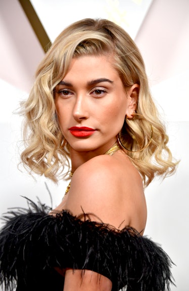 Hailey Baldwin, with curly hair and a red lip, attends the #REVOLVEawards at DREAM Hollywood on Nove...