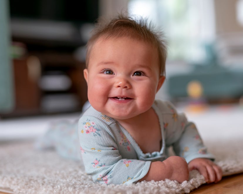 a sweet, smiling baby on their tummy in an article about when to start tummy time