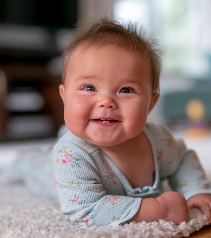 a sweet, smiling baby on their tummy in an article about when to start tummy time