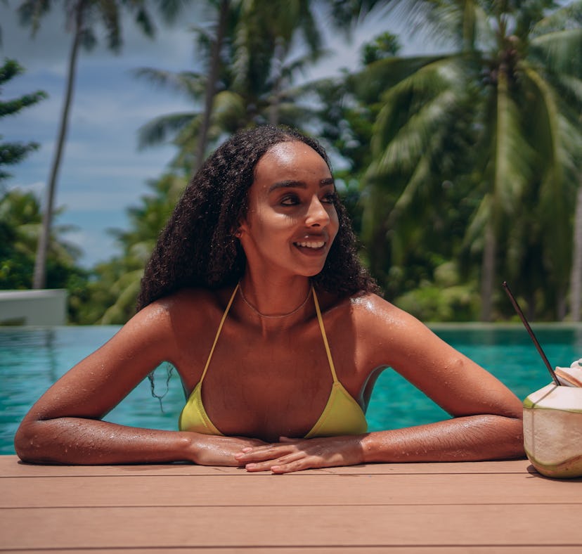 A woman in a pool is traveling based on the 2023 travel trends and predictions, according to experts...