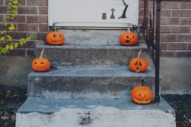 Bunch of carved pumpkins on a front stoop.