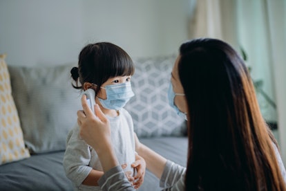 Young Asian mother checking sick daughter's temperature does child have covid/flu/rsv/cold?