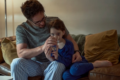 dad helping daughter hydrate and drink water while sick, does child have cold, cough, flu, or rsv