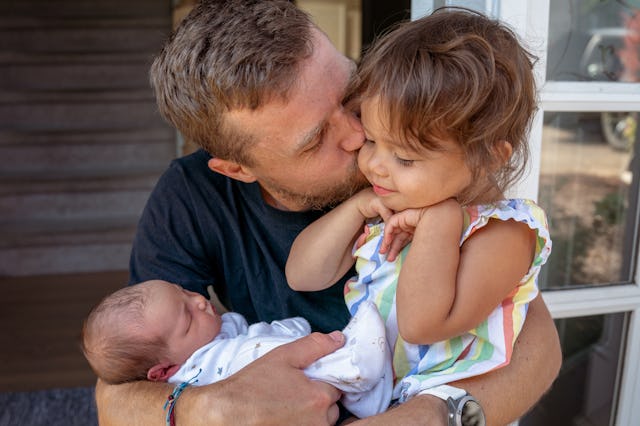 Tight shot of a father hugging his toddler daughter and giving her a kiss on the cheek while affecti...
