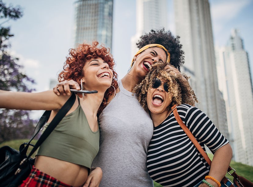 three women embrace and share a laugh together as they discuss the November 2022 new moon in sagitta...