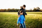 一个单身父亲和他的儿子在一起玩了一天后穿过公园。