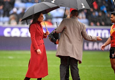 Catherine, Princess of Wales shelters from the rain under an umbrella