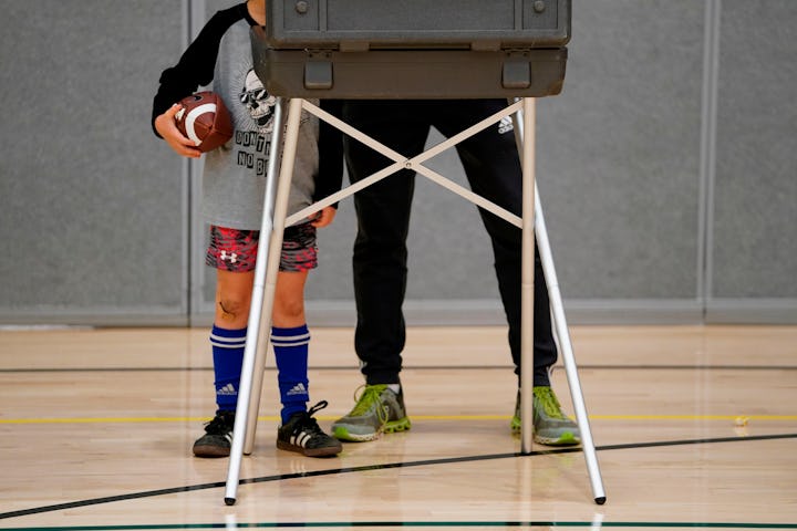 TOPSHOT - A young boy waits for his father to cast his ballot at Greenwich High School in Greenwich...