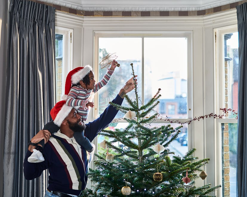 Father and daughter decorating Christmas tree in an article about can christmas trees catch fire?