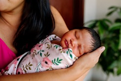 a newborn baby in a swaddle in an article about when to stop swaddling and signs it's time to stop.