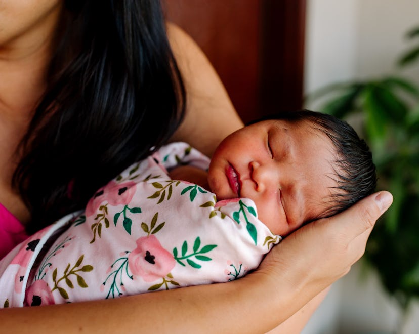 a newborn baby in a swaddle in an article about when to stop swaddling and signs it's time to stop.