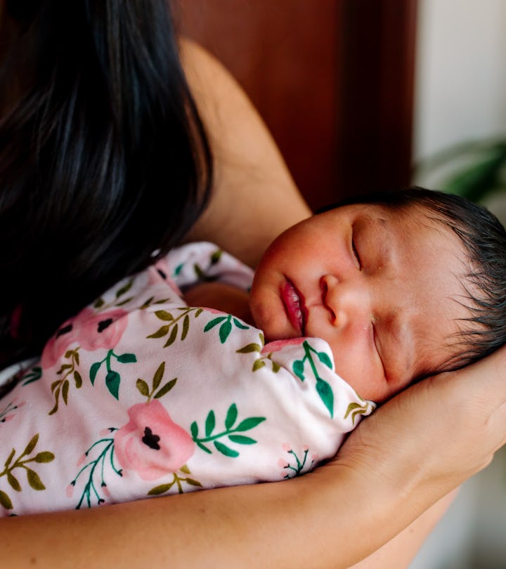 a newborn baby in a swaddle in an article about when to stop swaddling and signs it's time to stop.