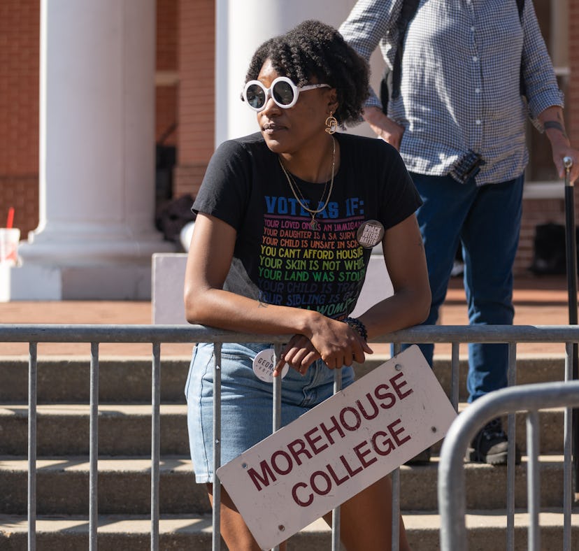 A woman stands against a fence before Sen. Raphael Warnock (D) speaks at a campaign event at Atlanta...