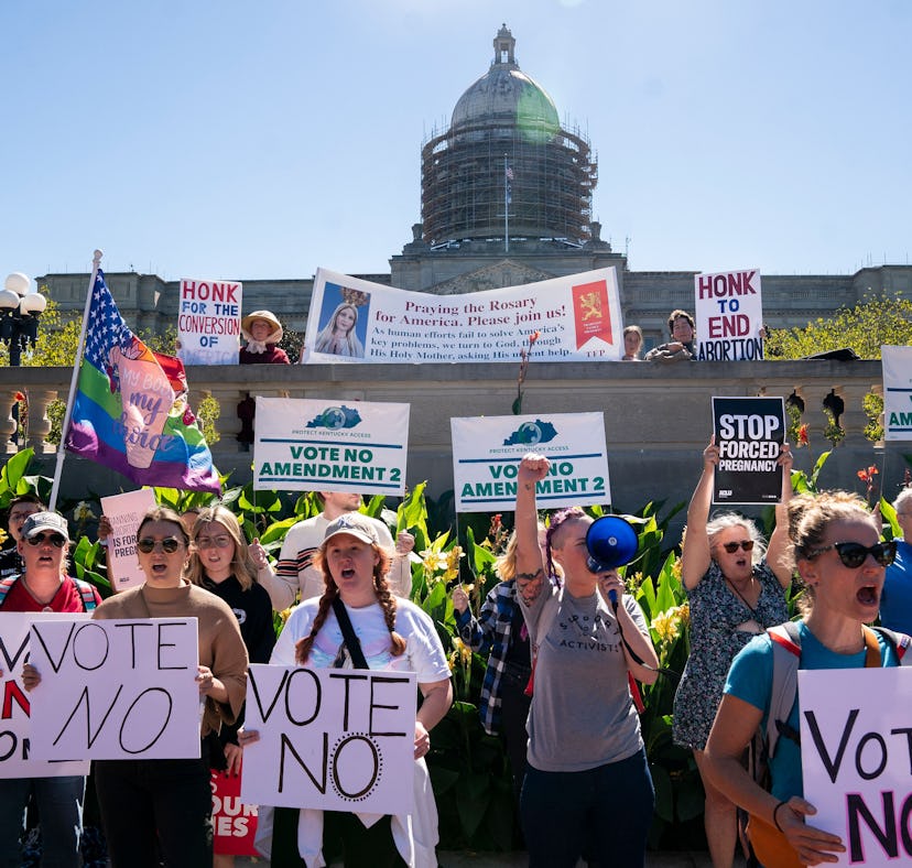 Counter-protestors hold signs in front of a rally encouraging voters to vote yes on Amendment 2, whi...