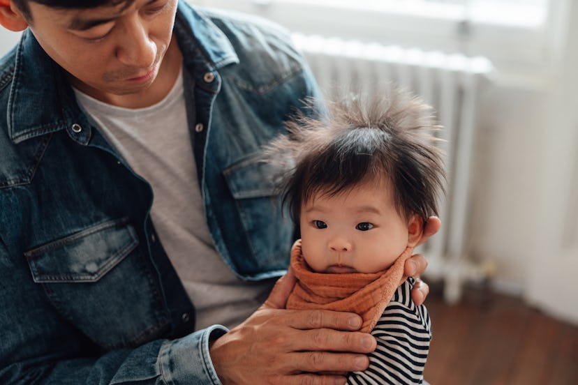 A dad burping his baby girl after feeding, in an article about can you burp a baby too hard?