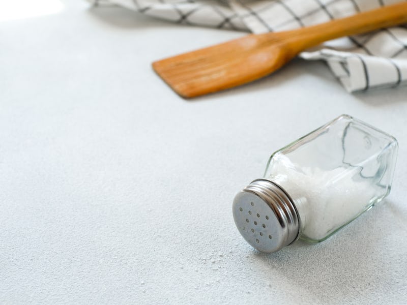 A new clean Wooden spatula, a kitchen towel and a salt shaker on the dining table. The concept of co...