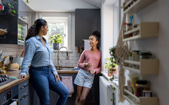 Mother and daughter bonding at home in the kitchen and talking